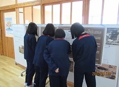 展示解説パネルを見学する中学生の画像