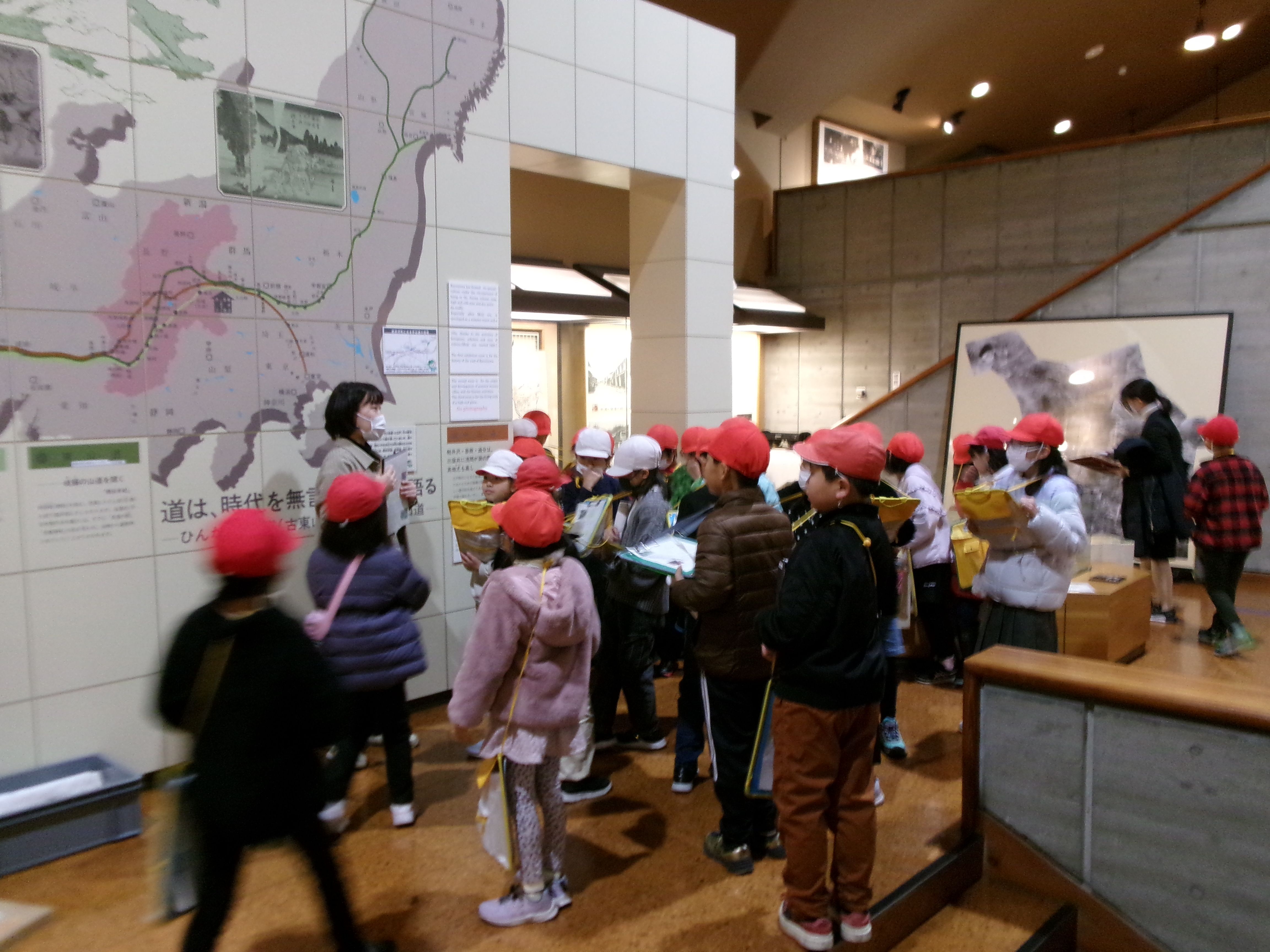 第1展示室にて学芸員の話を聞く児童の画像