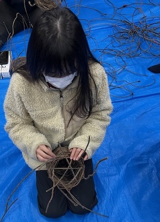 あけびのつるで編んでいる様子。の画像